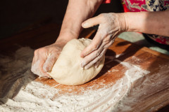 Senior woman hands knead dough on a table in her home kitchen