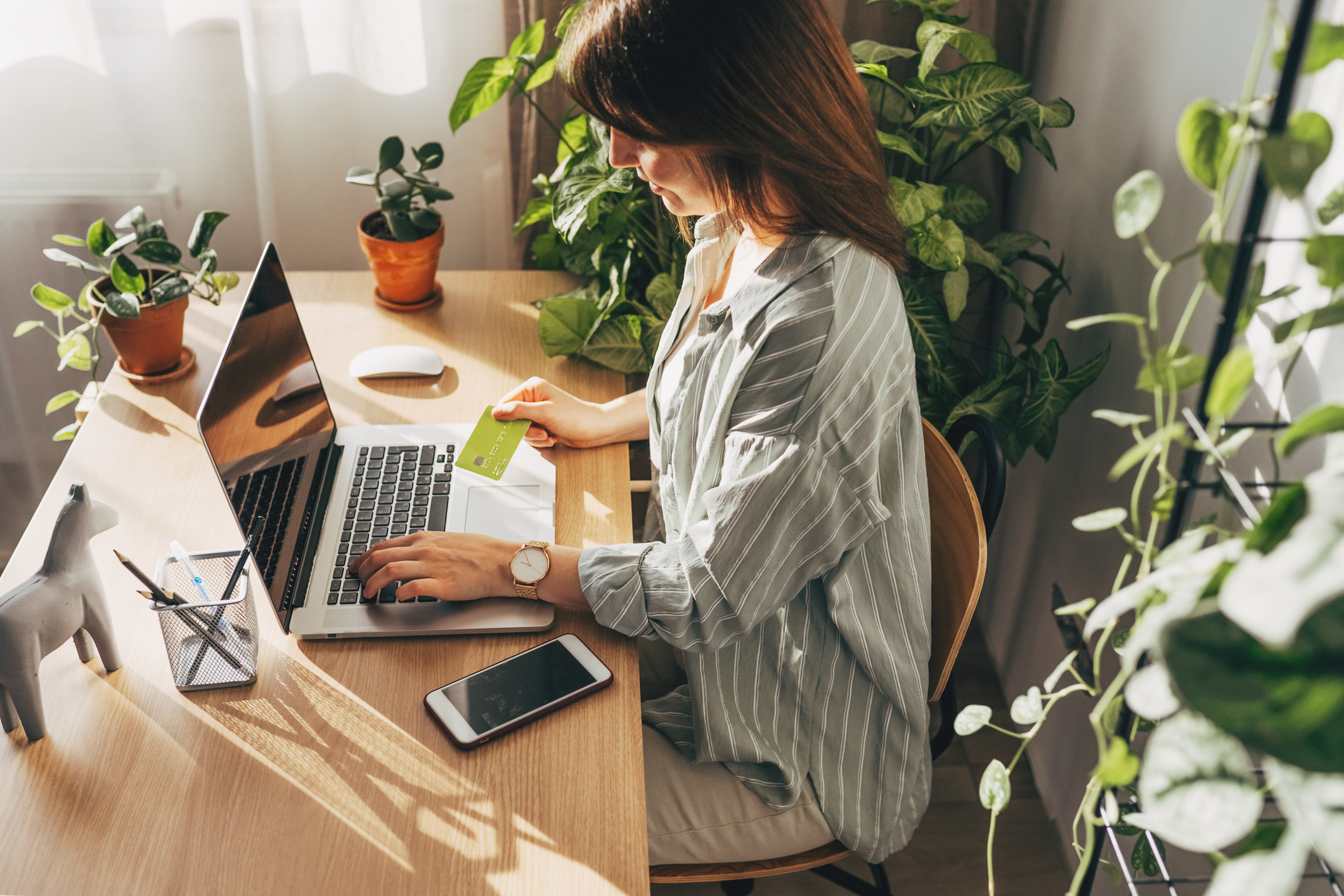 Young woman donor holding credit card and using laptop computer to make a donation online