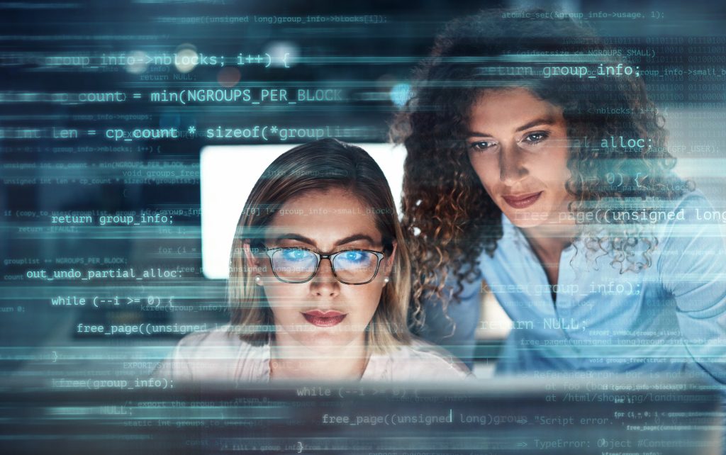 Businesswomen working in the office superimposed over multiple lines of computer code